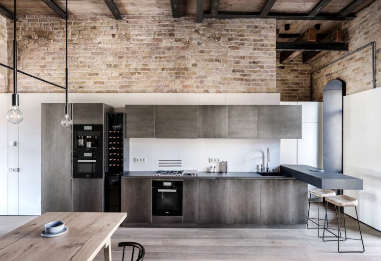 The kitchen is done with dark metal cabinets and a floating breakfast space with stools