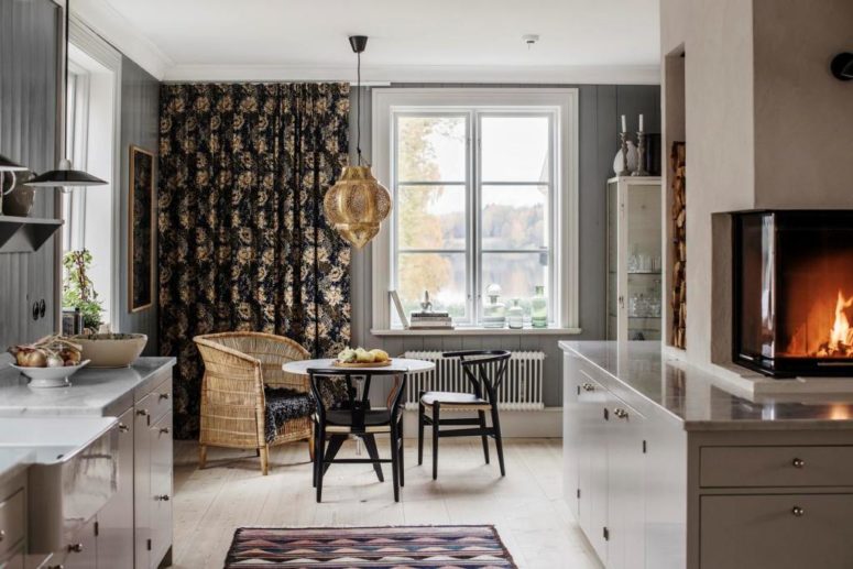 The kitchen island features a modern fireplace clad with glass and a firewood storage space