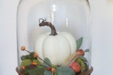 05 a cloche with a wooden base with moss, a faux pumpkin and berries and veggies plus foliage for a cozy feel