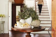 05 a large console table with fresh greenery in a vase, a wooden tray with pumpkins and gourds and an oversized pumpkin