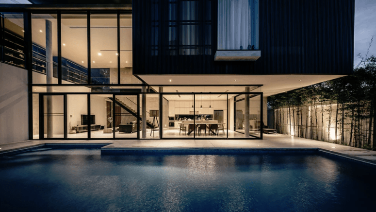 Extensive glazing opens the house to the garden and pool, which are still wrapped with a concrete fence to keep the privacy