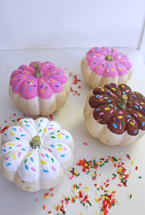 colorful pumpkins painted as glazed donuts with sprinkles for a fun and quirky touch