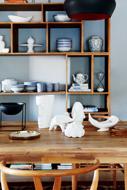 The dining space combines greys and light-colored wood, there's a stylish dining set and a large open storage unit