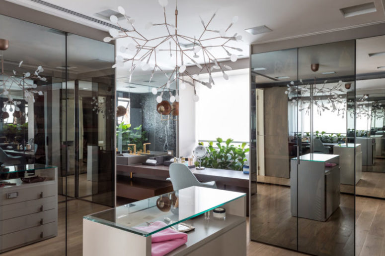 There's a large closet with glass and mirror surfaces and a bathroom integrated here for a spa feel