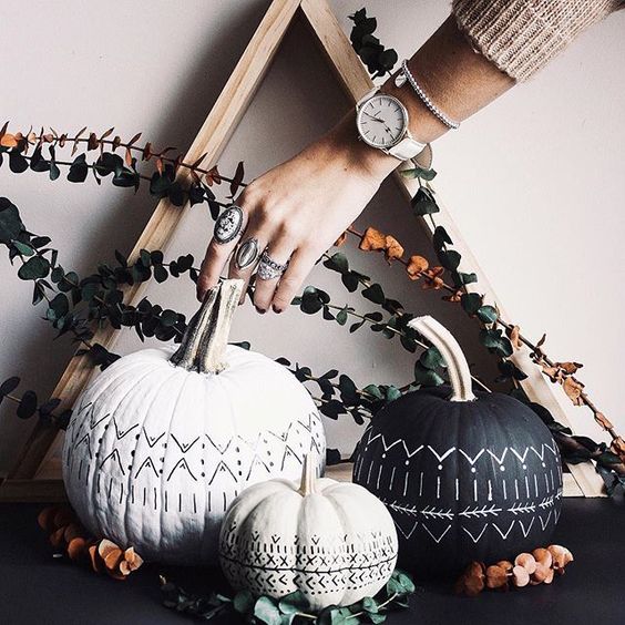 an arrangement of black and white pumpkins with tribal patterns with usual and dried eucalyptus