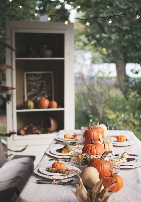 a cozy and simple Thanksiving table setting with pumpkins and corns plus corn husks