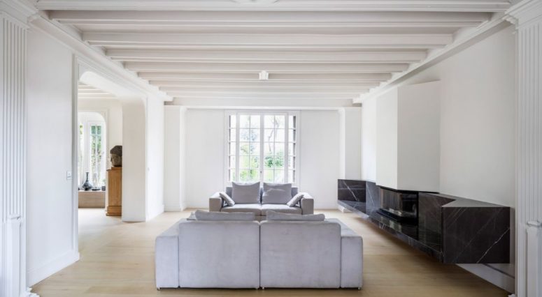 The living room is done with a double sofa and a gorgeous modern marble clad fireplace