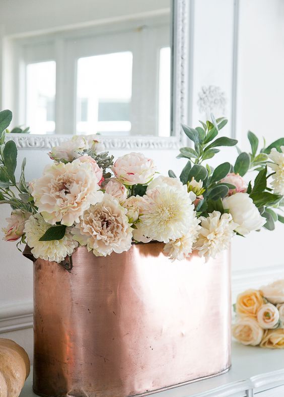a Thanksgiving centerpiece of a copper planter and white and blush blooms and greenery