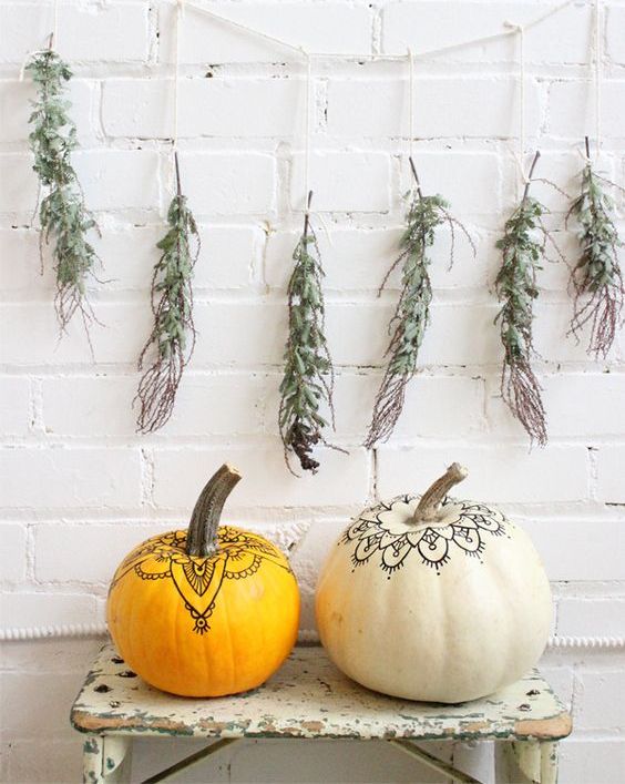 a duo of pumpkins decorated with a usual pen in a boho chic way look nice, a greenery garland adds a natural touch