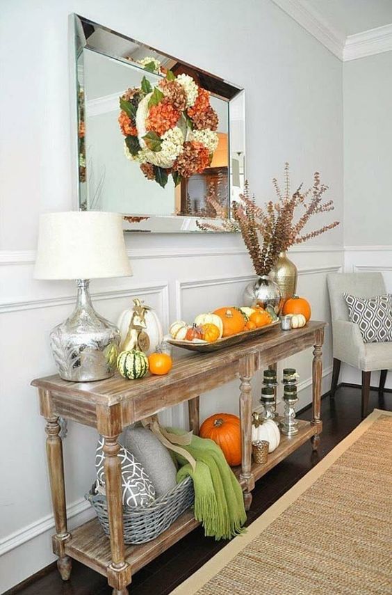 a rustic vintage console with real pumpkins, dried bloom wreaths, herbs, scarves and pillows