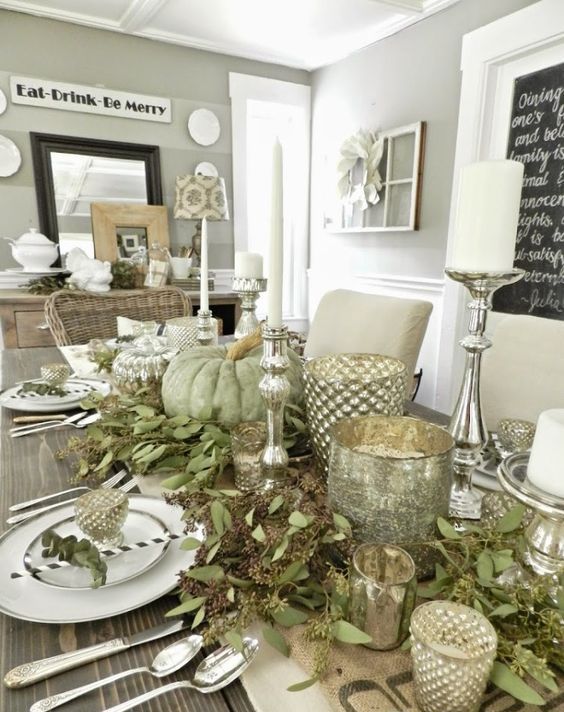 a cool table decorated with seeded eucalyptus, green pumpkins, mercury glass candle lanterns and candles