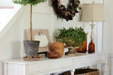 15 a vintage console with baskets, faux pumpkins, potted plants and a wreath of fake leaves and berries