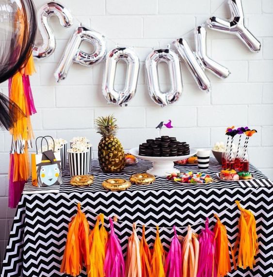 a colorful candy bar with a bright tassel garland and silver letter balloons plus a pineapple for a tropical feel