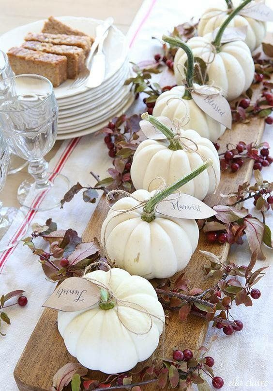 a natural rustic centerpiece of a cutting board, white pumpkins and berries for Thanksgiving