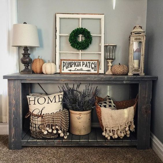 a rustic console with fabric and decopuage pumpkins, lavender, a boxwood wreath and scarves with pompoms