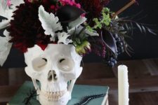 19 a skull vase with a moody and textural floral and greenery centerpiece with burgundy and plum touches