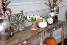 20 a vintage console with real pumpkins, dried herbs and greenery and firewood in a galvanized bucket