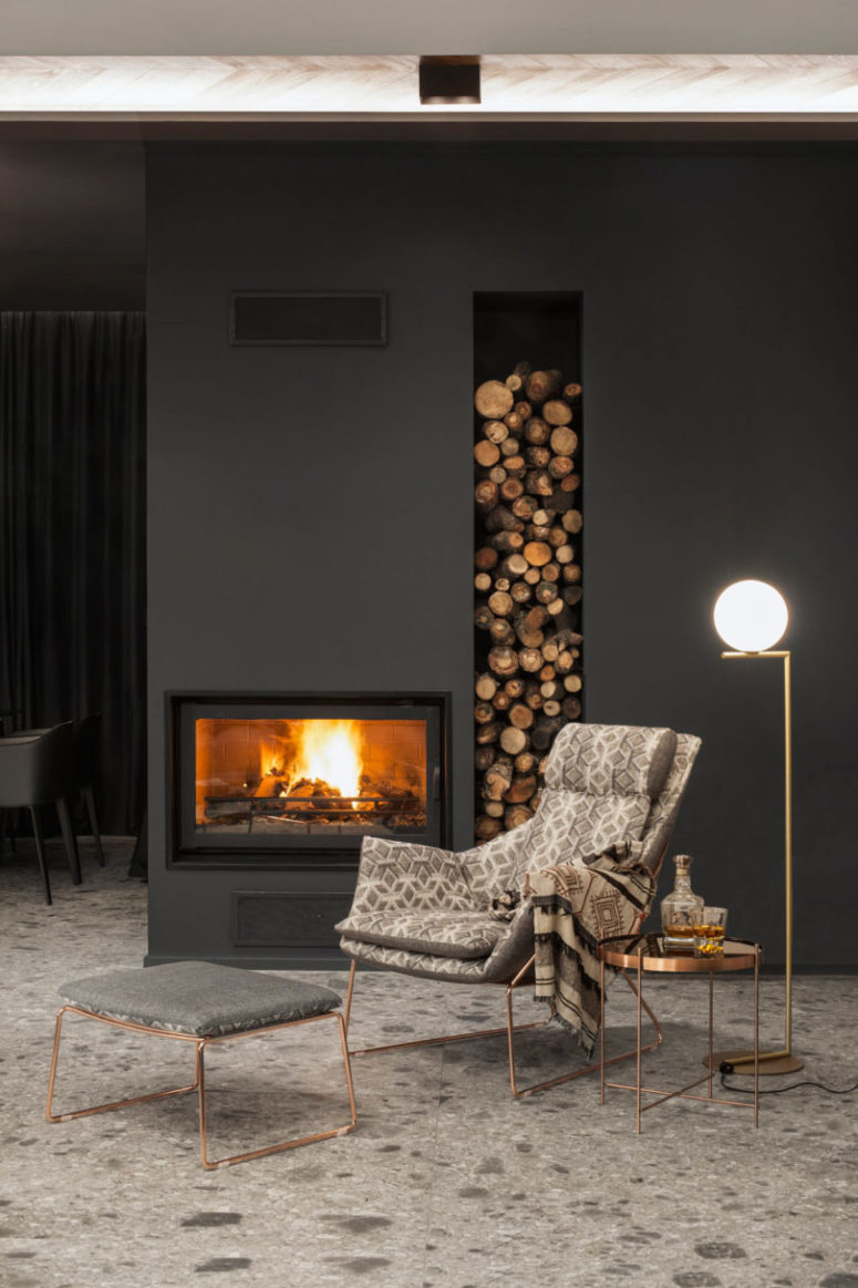 Stone, graphite and black surfaces were softened with wood and warm metals copper and gold plus a firewood storage unit like here Stone, graphite and black surfaces were softened with wood and warm metals - copper and gold plus a firewood storage unit like here