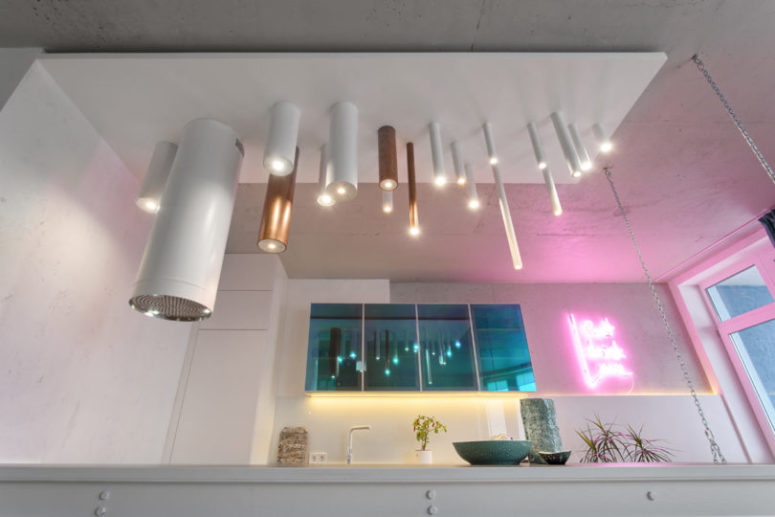 The kitchen is illuminated with tube-like lamps and a pink neon light