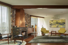 02 The living room features a large fireplace clad with stone and copper, lemon yellow chairs and a matching artwork plus colorful rugs that cozy up the space