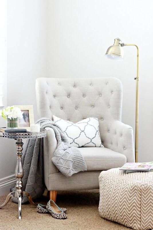 a reading nook with a comfy traditional chair, an ottoman, a coffee table, a floor lamp