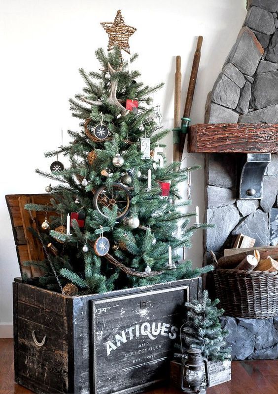 a rustic Christmas tree with antlers, wood slice ornaments, a twig star on top, branches and an antique crate as a base