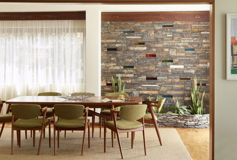 The dining room is done with stone clad wall and a stone planter, with a dining table and chairs with comfy upholstery