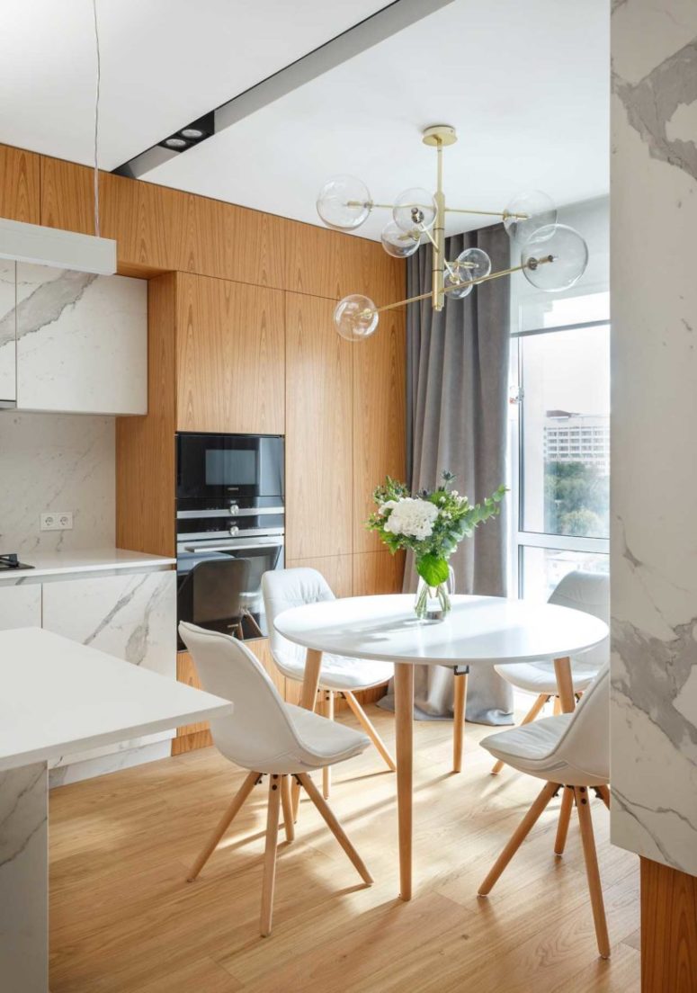 The dining space is by the window, with a round table and modern chairs