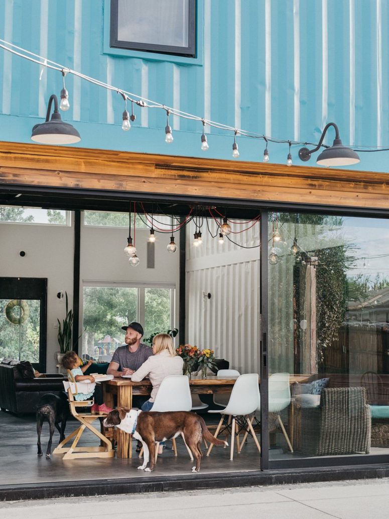 The dining space is done with a wooden table, modern chairs and with bulbs over the dining set