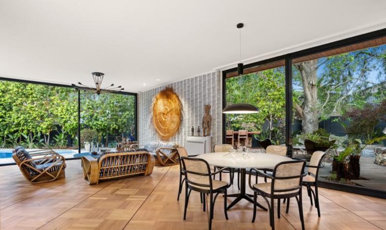 The dining space is located next to a glazed wall, there are rattan chairs and a table