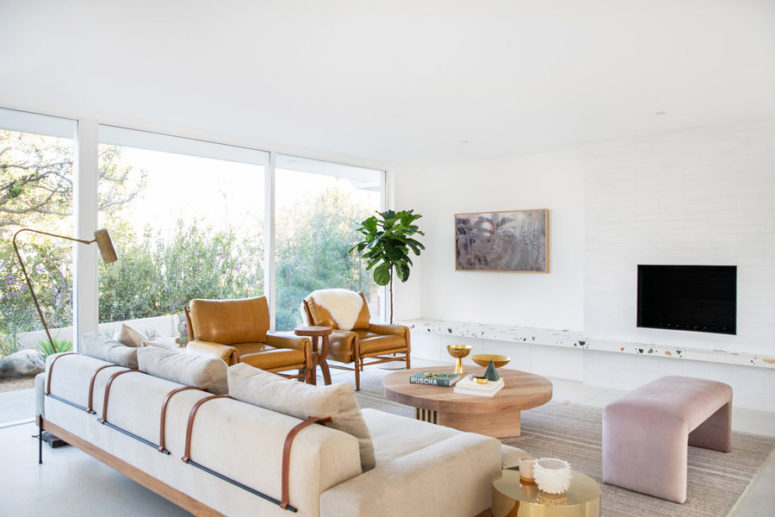 The living room is an airy space, there's neutral comfy furniture, a terrazzo shelf and side tables