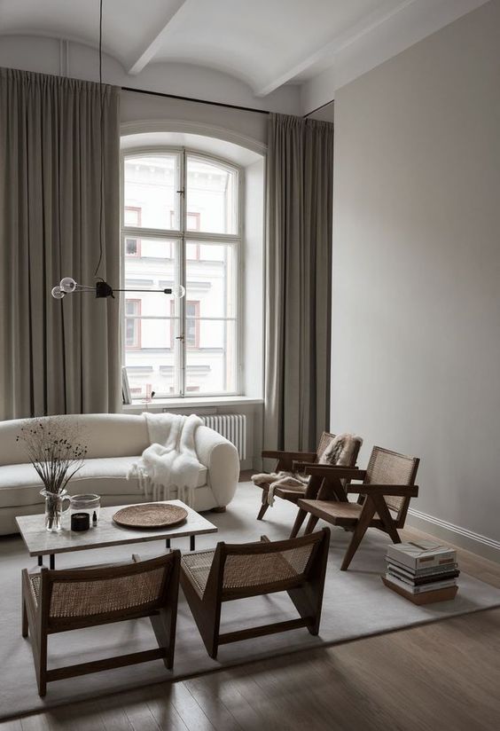 a contemporary living room styled in light greys, with woven chairs, enough light coming from large windows
