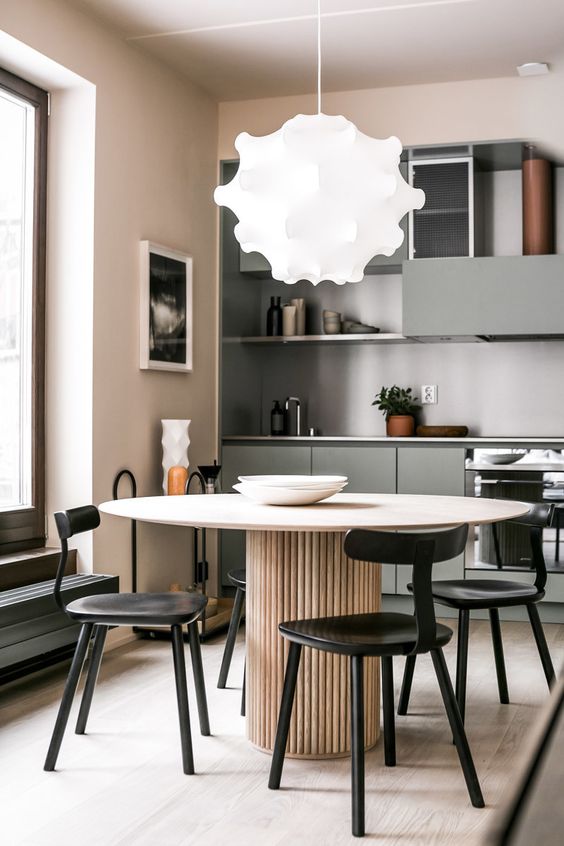 a soft pastel minimalist kitchen in blush, beige and with touches of muted green plus black chairs