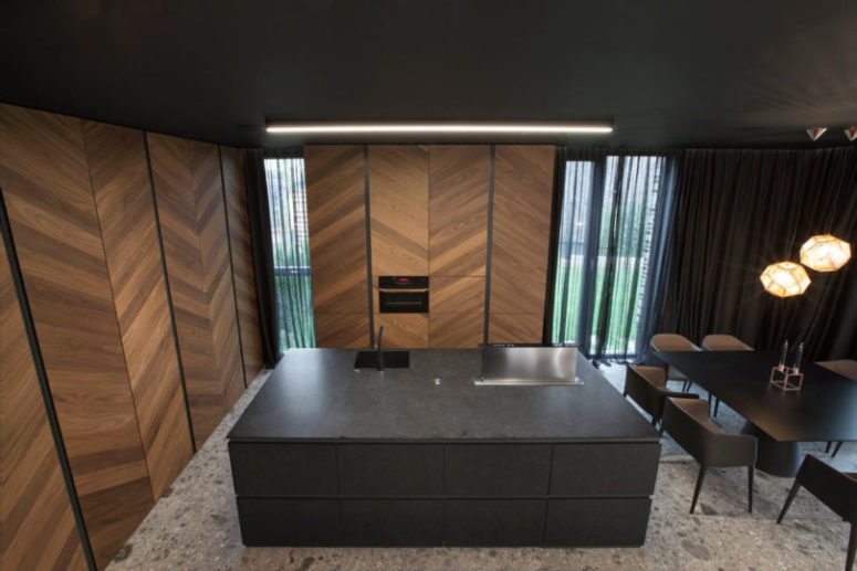 The kichen is done with wooden cabinets that hide everythign behind the doors and a black kitchen island The kichen is done with wooden cabinets that hide everythign behind the doors and a black kitchen island