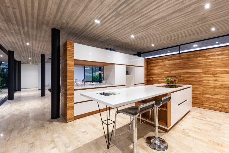 The kitchen is done with sleek white cabinets, it's separated with a half wall from the dining space