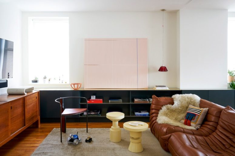 The living room is a chic space with a gorgeous leather sofa, small coffee tables and a wooden sideboard, some of furniture is handmade for this home
