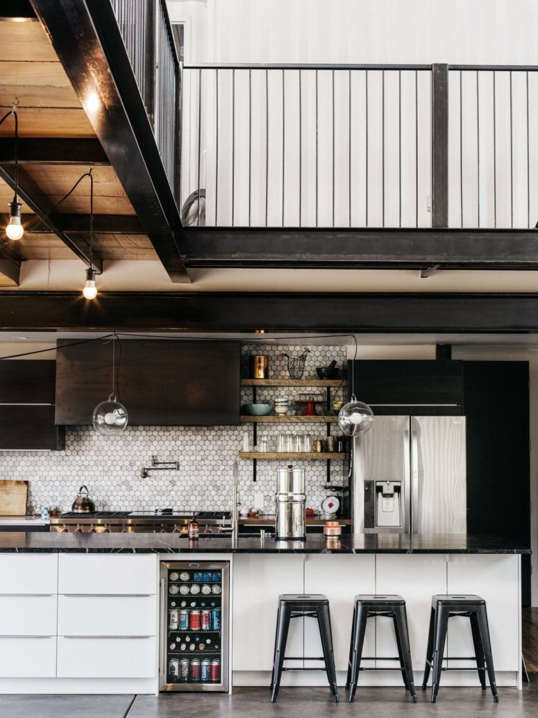 The kitchen features black cabinets, a large kitchen island with a black stone top and a marble hex tile backsplash