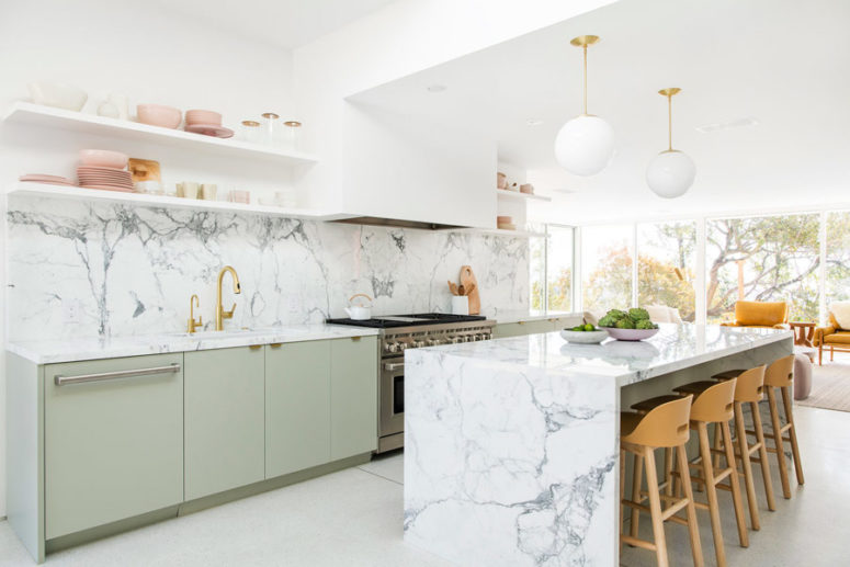 The kitchen is done with light green cabinets and the surfaces are covered with stone