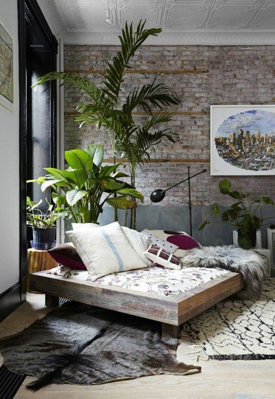 a neutral industrial space done with boho touches, animal skins, brickwork and potted plants make it catchy