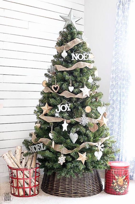 a super cozy Christmas tree with various star ornaments including wooden ones, burlap ribbons, snowflakes and hearts plus a basket cover