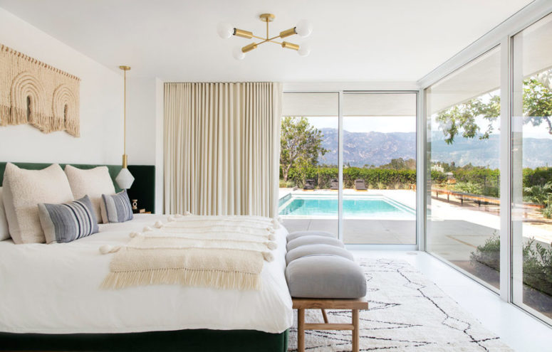 The bedroom is furbished with an upholstered bed, a rug, three walls are glazed and there's an entrance to the outdoor space