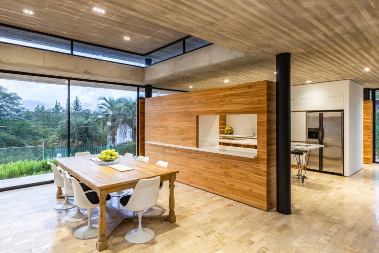The dining space is done with modern white chairs and a wooden table
