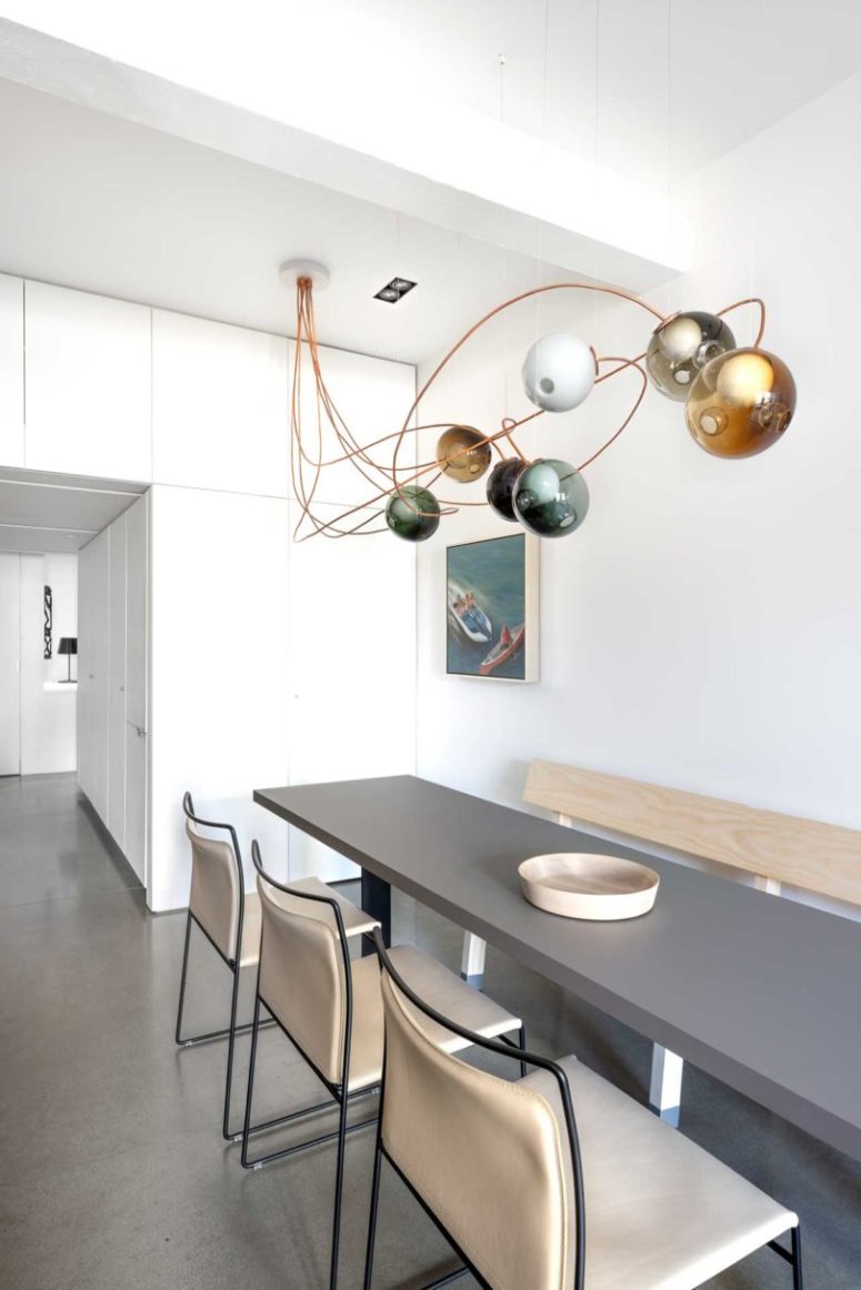 The dining space shows off a long grey table, comfy leather chairs and a gorgeous bubble lighting over the set