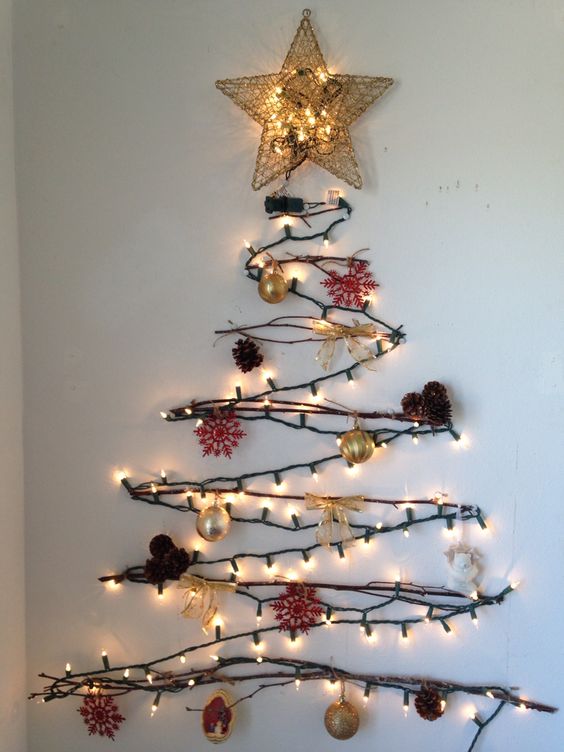a cool wall-mounted Christmas tree of branches, lights and with pinecones and goldd ornaments as an alternative tree