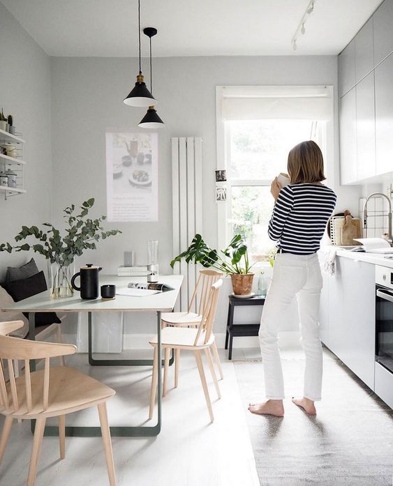 a light and air-filled kitchen in light grey and white plus natural wood chairs