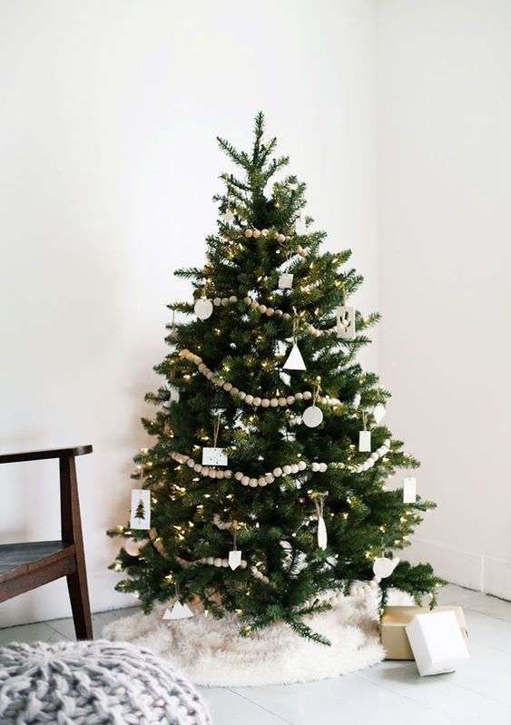 a modern Scandinavian Christmas tree with wooden bead garlands, white cardboard and clay ornaments in various shapes