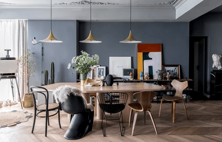 The dining space is done with a wooden table and mismatching chairs of plywood and metal