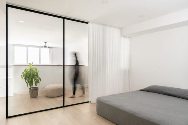 The minimalist bedroom is divided from the rest of the space with glass and there's a large bed