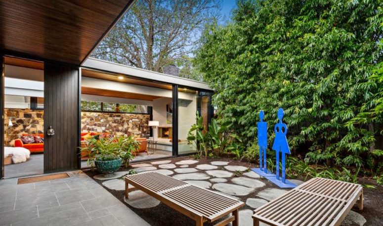 This space features lush greenery and bushes, a couple of benches and fun and colorful blue figures