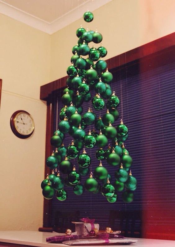 a small suspended Christmas tree of shiny, matte and glitter emerald ornaments hanging on different heights